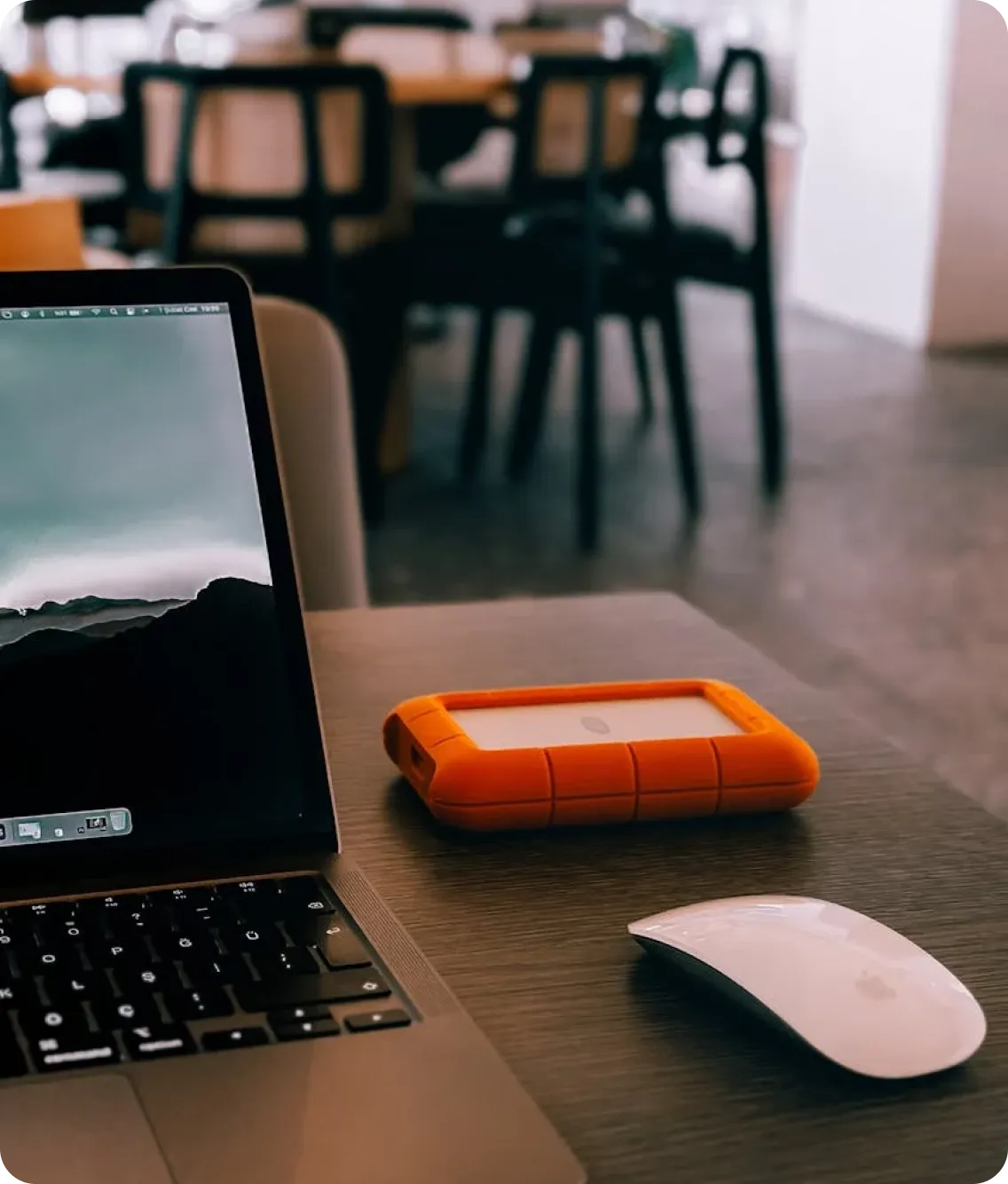 A close-up shot of a MacBook, a mouse, and a miscellaneous electronic device, all used in online translation jobs.
