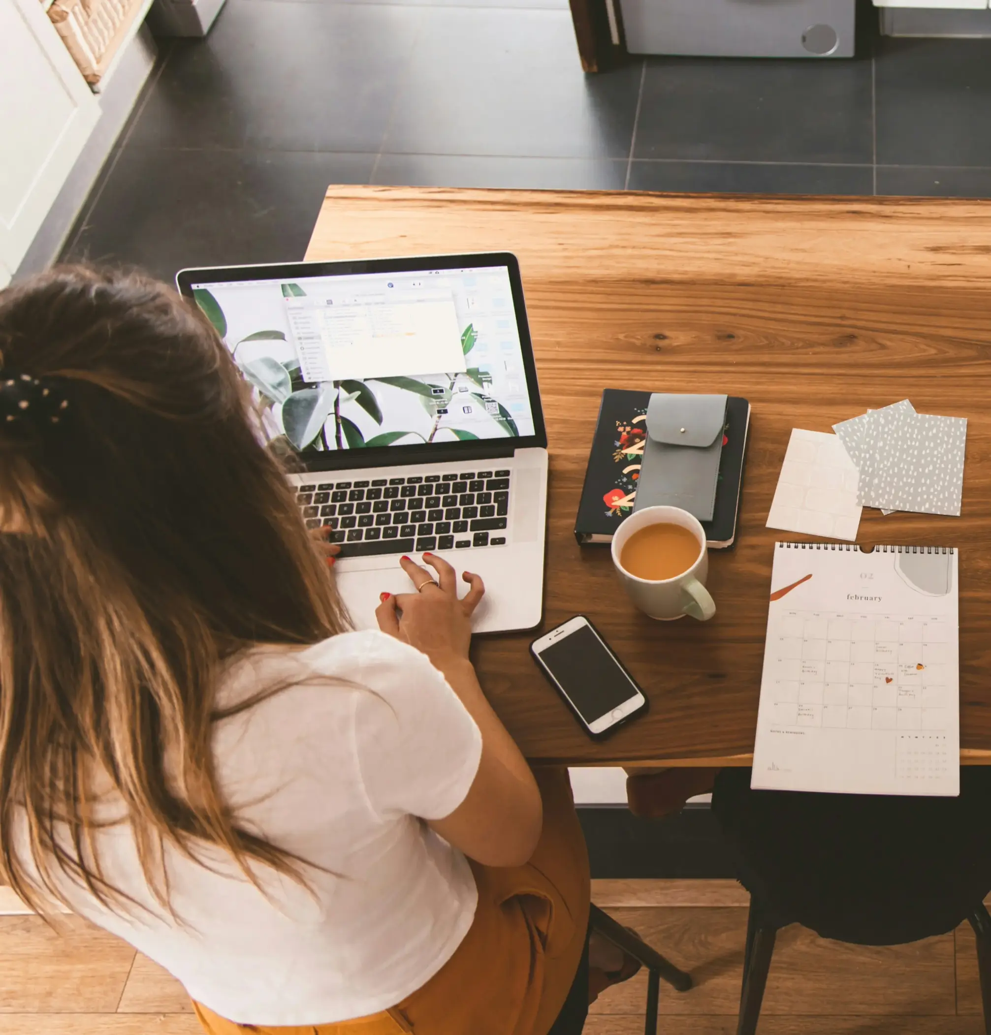 A young female sits in front of her computer working with a cup of tea and stationary around her at the translation and marketing agency Aurora Hikma.