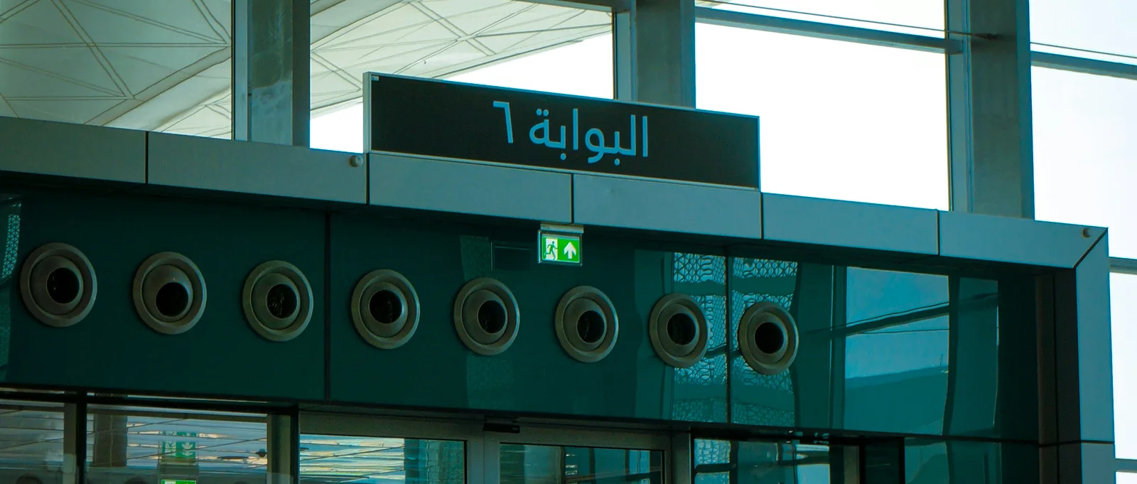 Airport gate signage in the Gulf reading البوابة ٦: Arabic-first wayfinding, localized at the structural level